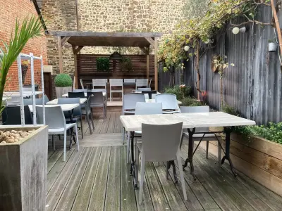 Terrasse en bois de la crêperie Mamilig, tables et chaises, grande table sous la pergola, murs de pierre